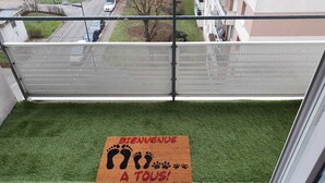 Un balcon agrémenté d’un revêtement de sol en gazon synthétique et d’un paillasson orné d’empreintes de pas et d’empreintes de pattes.