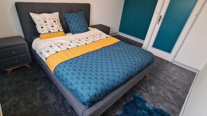 Une chambre à coucher avec un lit, des tables de chevet, une commode et un tapis bleu.