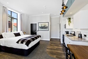 Une chambre d’hôtel moderne avec un grand lit, un petit coin cuisine et une vue sur le bâtiment extérieur.