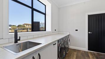 A modern kitchen with a large window, a stainless steel sink, and a black door.