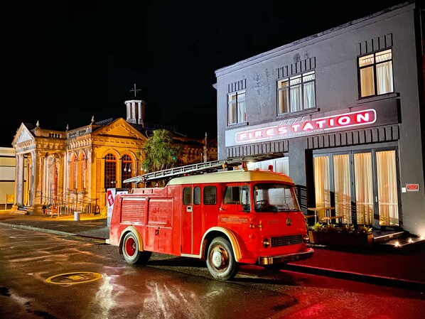 Une ancienne caserne de pompiers rouge, au design classique, située à côté d’un bâtiment sur lequel on peut lire l’inscription « Caserne de pompiers ».