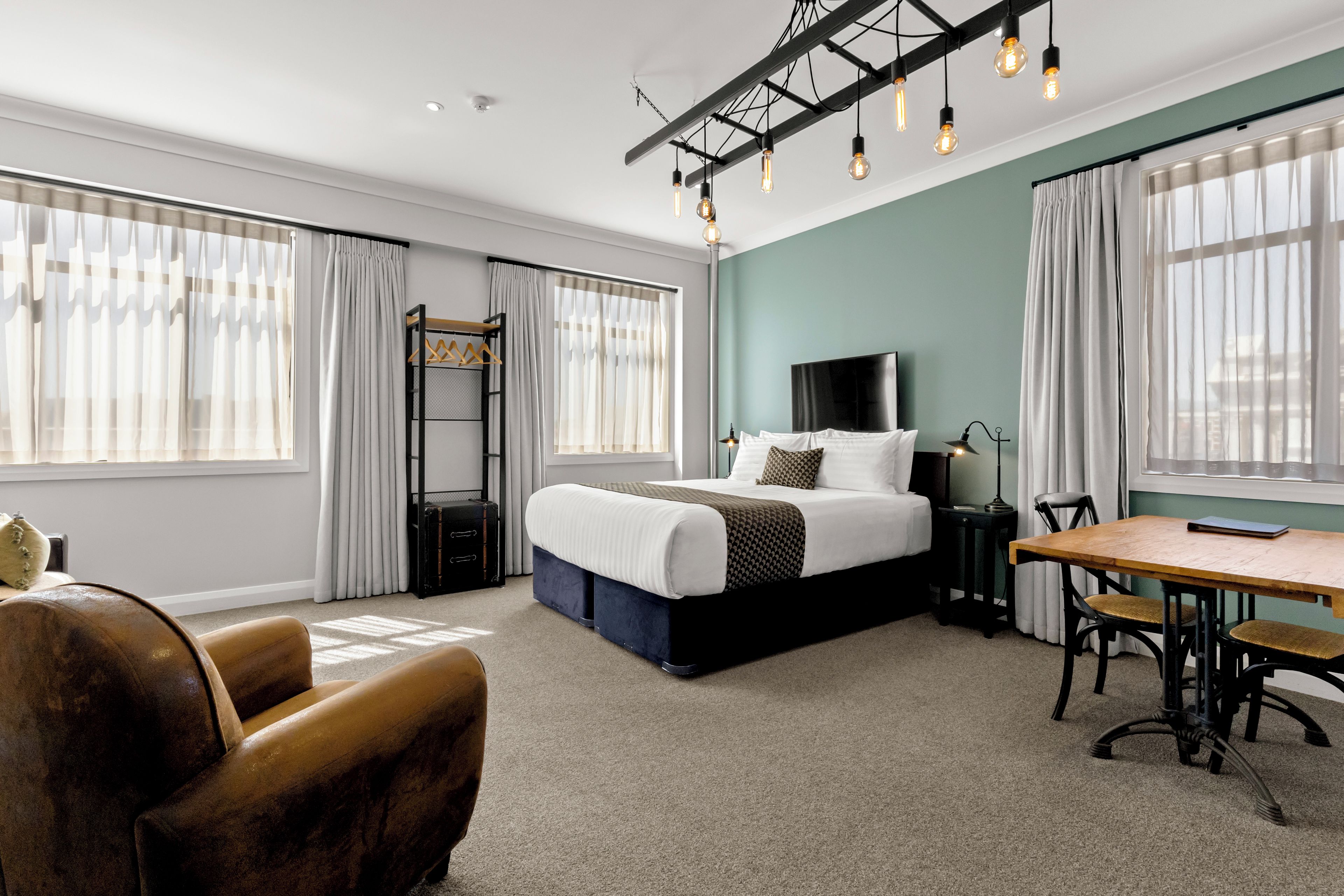 Una habitación de hotel moderna con una cama grande, un escritorio y una silla.
