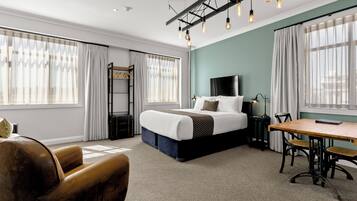 A modern hotel room with a large bed, a desk, and a chair.