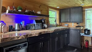 A modern kitchen with wooden cabinets, a countertop coffee maker, a toaster, and a sink. - Cozy cottage in paradise! Cross Lake, Aroostook County (Cross Lake Township)