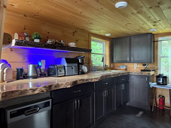 A modern kitchen with wooden cabinets, a countertop coffee maker, a toaster, and a sink. - Cozy cottage in paradise! Cross Lake, Aroostook County (Cross Lake Township)