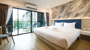 Habitación de hotel moderna con una cama grande, un balcón con una silla y vistas al exterior.