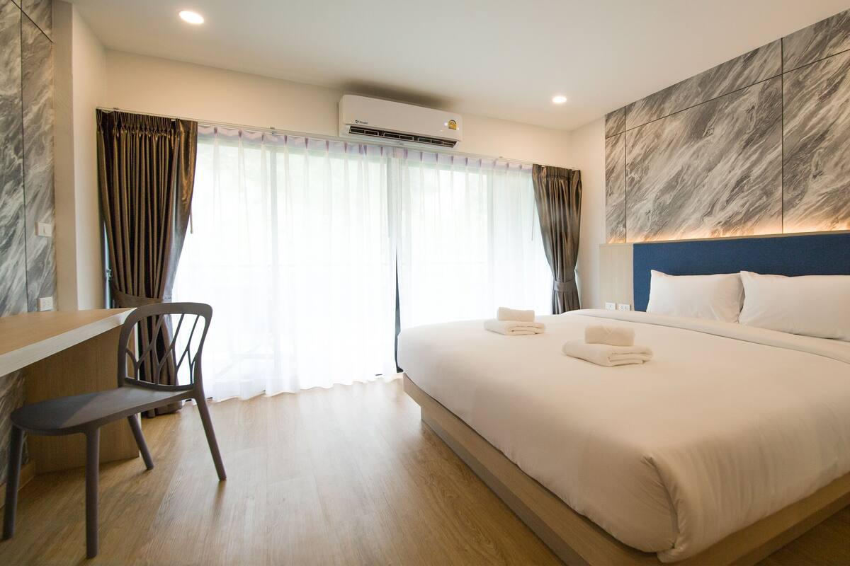 Una habitación de hotel con una cama grande, un escritorio, una silla y un diseño de pared moderno.