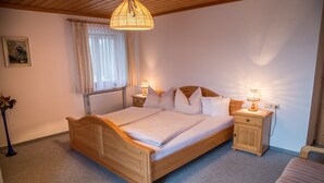 Une chambre à coucher avec un lit en bois, deux tables de chevet avec des lampes, un radiateur et une fenêtre avec des rideaux.