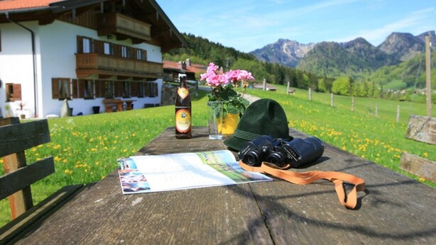 Une table en bois sur laquelle on trouve une carte, un appareil photo, une bouteille et un chapeau.