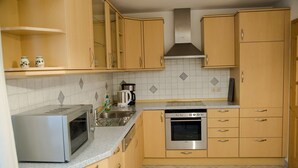 Une cuisine avec des meubles de rangement en bois, un four à micro-ondes, une machine à café et un lave-vaisselle.