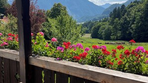 Una terraza de madera con vistas a un paisaje montañoso y un campo con vacas.
