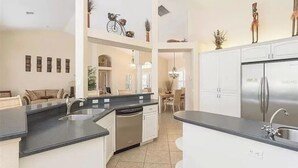 Una cocina moderna con una isla central, electrodomésticos integrados y un comedor con candelabro.