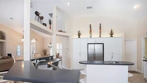 Una cocina moderna con armarios blancos, una isla central y un refrigerador integrado.