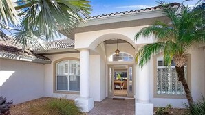 Una casa con un porche cubierto, ventanas amplias y una puerta que da a un espacio interior con comedor.