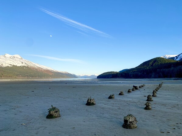 A beach with a row of rocks in the foreground and mountains in the background.
