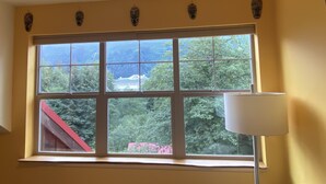 Ein Zimmer mit großem Fenster, ein rotes Dach ist draußen sichtbar, und eine weiße Lampe auf der rechten Seite.