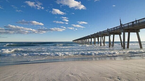 A beach with a pier extending into the ocean.