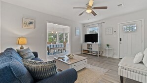 A living room with a sofa, coffee table, TV, and a ceiling fan.