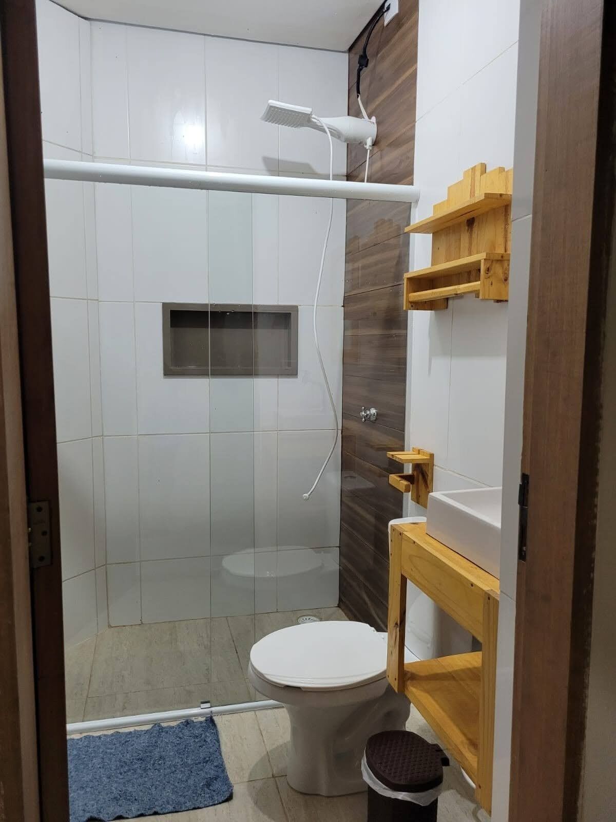 A compact bathroom with a shower, toilet, and wooden vanity.
