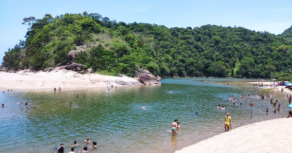 A beach with people swimming and sunbathing, surrounded by lush greenery and rocky outcrops. - Beach house, Sapê - Maranduba, dead end street, tranquility and beautiful landscape! (Ubatuba)