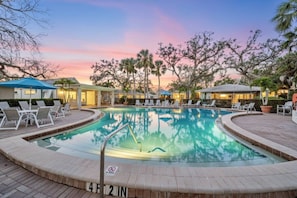 A pool area with lounge chairs and umbrellas, surrounded by trees and buildings. - Siesta Key Villa | Pool + Free Daily Activities (Siesta Key)
