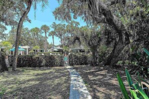 A pathway leading through a garden with trees and a building in the background. - Siesta Key Villa | Pool + Free Daily Activities (Siesta Key)