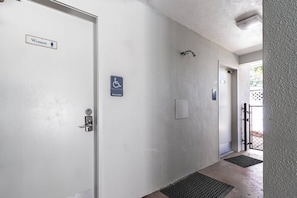 A hallway with a women’s restroom door, an accessible sign, and a door leading to another room. - Siesta Key Villa | Pool + Free Daily Activities (Siesta Key)