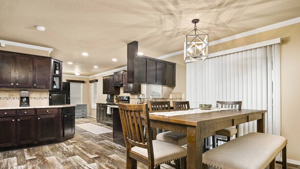 A spacious kitchen with dark wood cabinets, a central island, and a dining area with a wooden table and chairs. - Newly Constructed, Single Level, Open Layout, Walk to Sandy River, 17 Miles to Government Camp (Rhododendron)