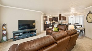 A living room with a brown leather sofa, a flat-screen TV, and a bookshelf. - Newly Constructed, Single Level, Open Layout, Walk to Sandy River, 17 Miles to Government Camp (Rhododendron)