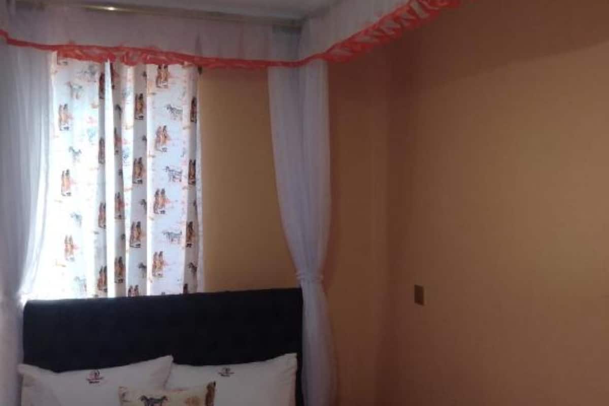 Ein Schlafzimmer mit einem Bett, einem Nachttisch und einem Fenster mit Vorhängen.