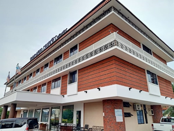Un hotel de varios pisos con fachada de ladrillo, balcones y una zona de estar exterior cubierta.