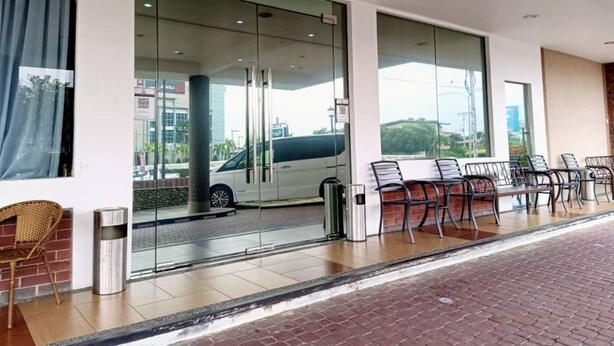 Una entrada de hotel moderna con puertas de vidrio, un área de estar al aire libre cubierta y vistas a la calle.