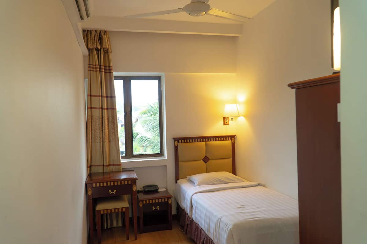Une chambre à coucher avec un lit, une table de chevet, une lampe et une fenêtre avec des rideaux.