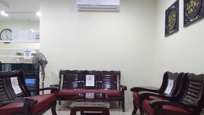 Zona de recepción con un conjunto de sofás, un ventilador y una mesa.
