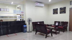 Un área de recepción con mostrador, sillas, un ventilador y suelo de baldosas.