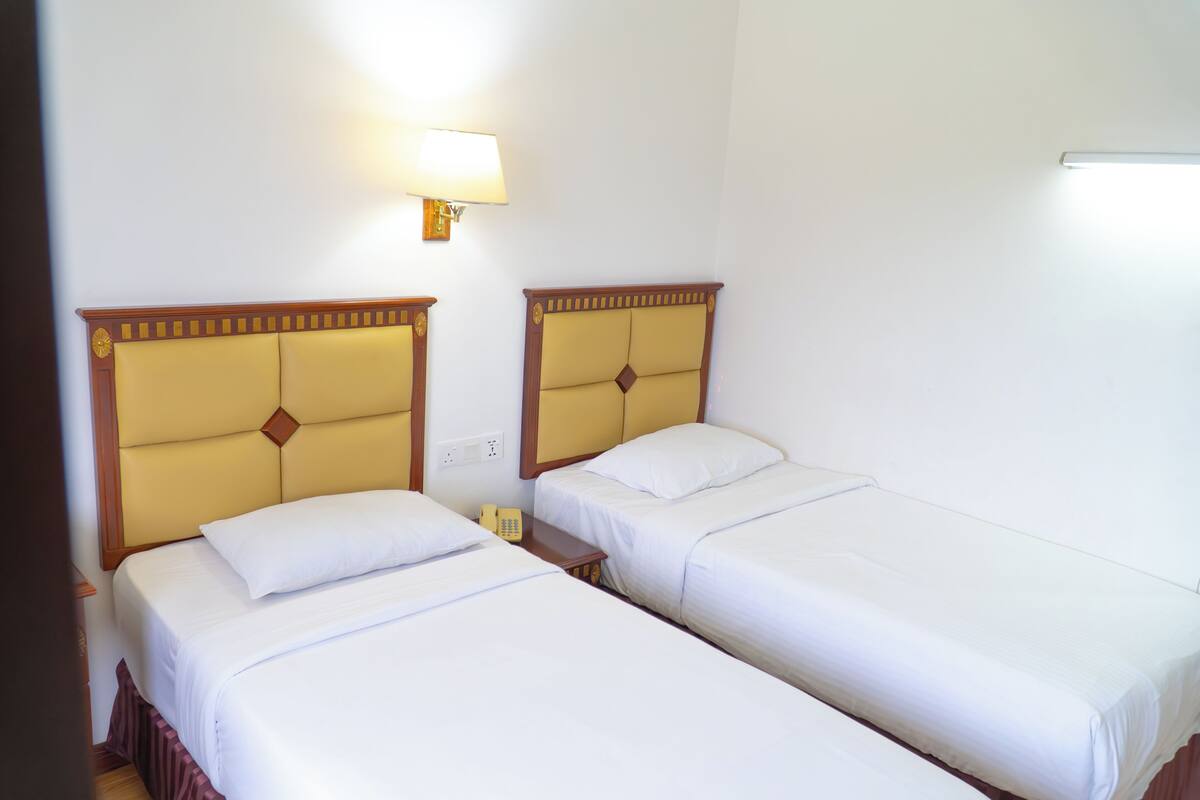 Une chambre d’hôtel avec deux lits, une table de chevet avec une lampe et un téléphone.