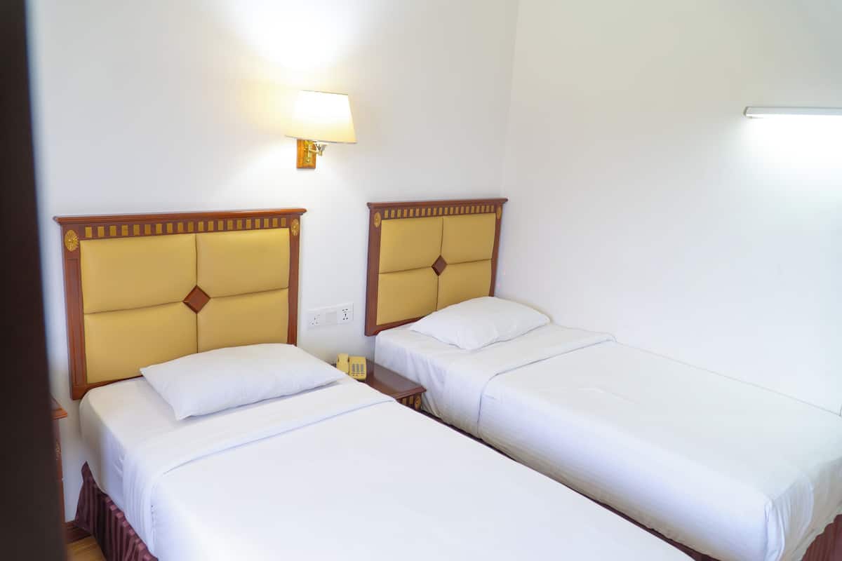 Une chambre d’hôtel avec deux lits, une table de chevet avec une lampe et un téléphone.