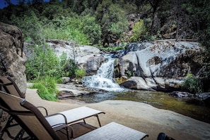 Entorno natural con cascada, mesa de picnic y banco.