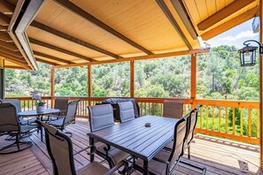 A covered outdoor patio with wooden flooring, a table, and chairs.