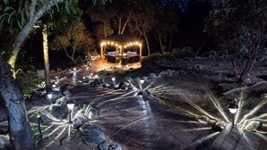 An outdoor seating area with a gazebo, surrounded by a stone pathway with embedded lights.