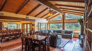 A spacious living area with a high ceiling, large windows, and a cozy seating arrangement.