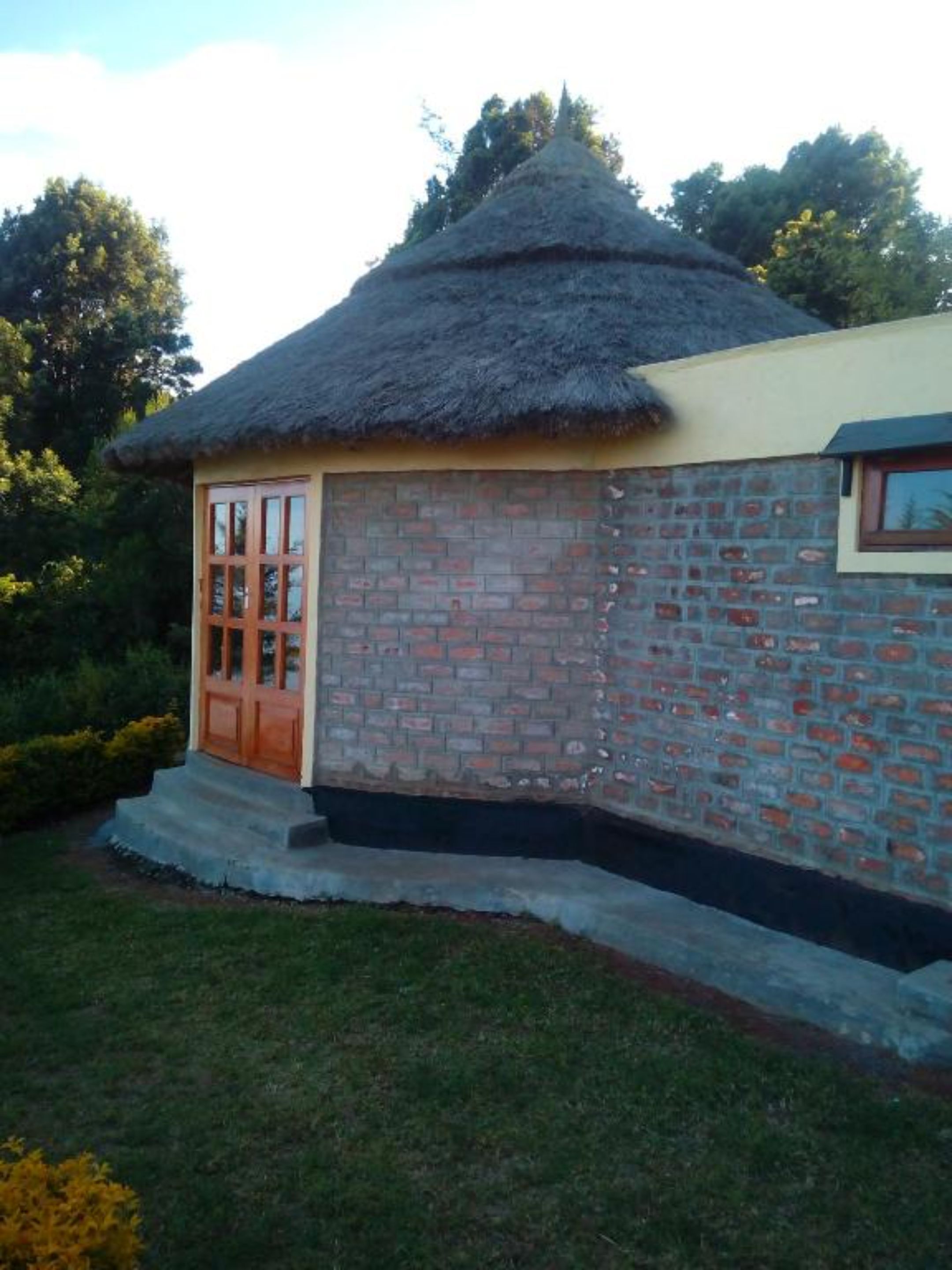 A small building with a thatched roof and a brick exterior.