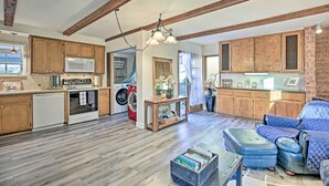 A spacious living area with wooden flooring, a blue leather sofa, a dining table, and a kitchen area with wooden cabinets and appliances. - Quaint La Mesa Home with Beautiful Sunsets! (La Mesa)