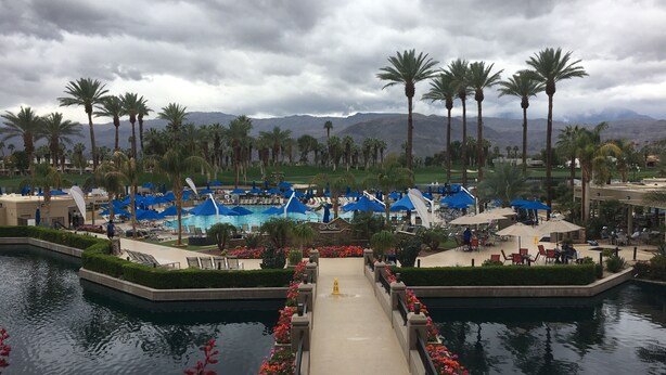 A resort with a pool area, lounge chairs, and palm trees.