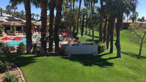 A resort with a swimming pool, palm trees, and a well-maintained lawn.
