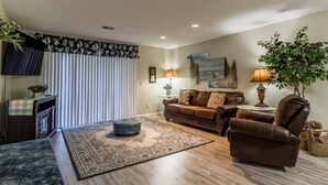 A living room with a sofa, armchair, and ottoman, a television, and a fireplace. - Branson Condo on Thousand Hills Golf Course with Indoor Pool and Hot Tub (Branson)