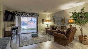 A living room with a sofa, ottoman, and a television on a stand. - Branson Condo on Thousand Hills Golf Course with Indoor Pool and Hot Tub (Branson)