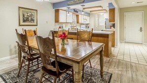 A dining area with a wooden table, four chairs, a vase of flowers, and a ceiling fan. - Branson Condo on Thousand Hills Golf Course with Indoor Pool and Hot Tub (Branson)