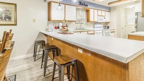 A modern kitchen with a central island, bar stools, pendant lighting, and a 'Kitchen' sign above the cabinets. - Branson Condo on Thousand Hills Golf Course with Indoor Pool and Hot Tub (Branson)