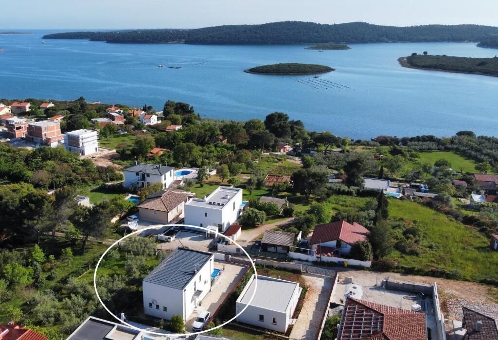 Luchtbeeld van een kustgebied met woningen, water en een klein eiland.